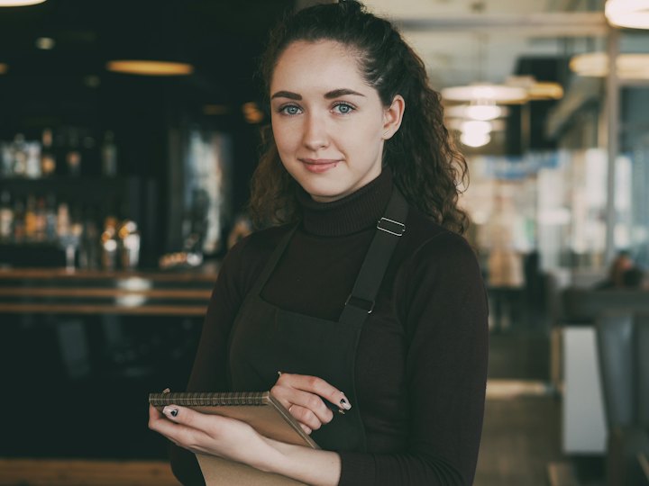Restaurant server in an apron holding a notepad