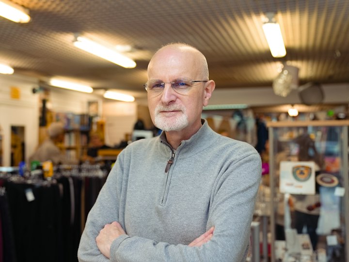 Shop owner standing with arms crossed in his store